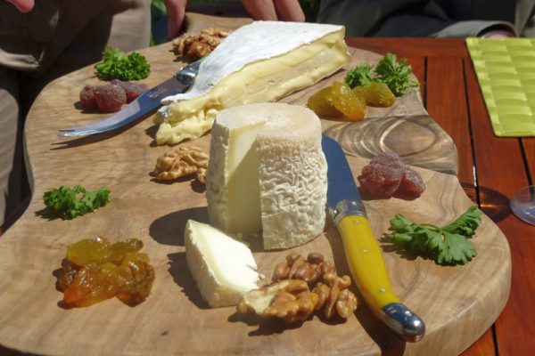 Soft cheese on wooden board with nuts and dried fruits
