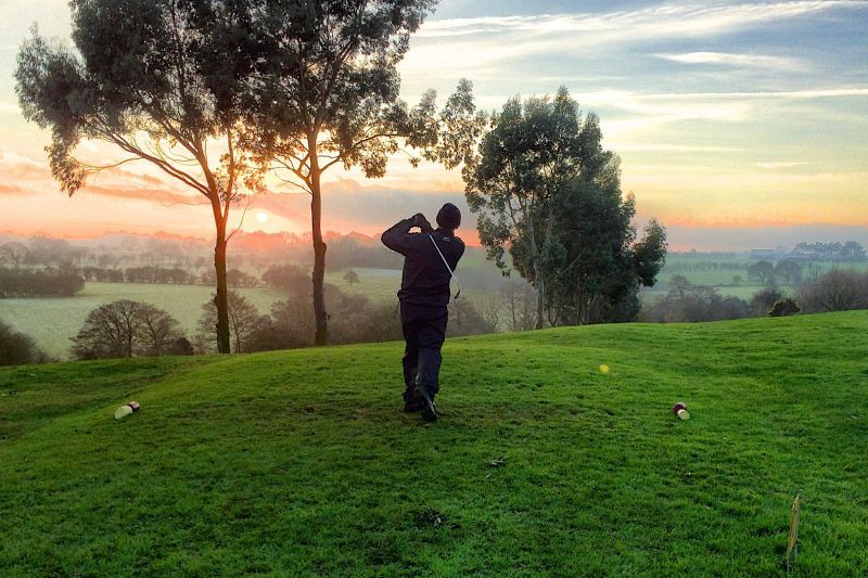 Person hitting the ball with the sun rising and the mist coming through