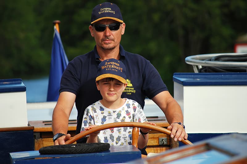 Child steering a barge with the Captain
