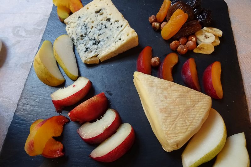 Cheese on serving slate with apple and dried fruit
