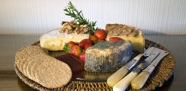 Selection of cheeses with knives and strawberries on a cheeseboard