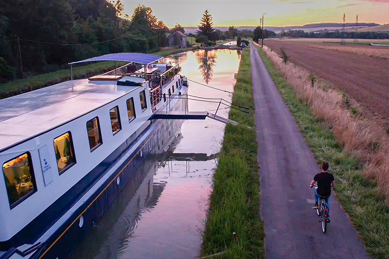 Cycling at sundown on the towpath next to hotel barge La Belle Epoque in Burgundy