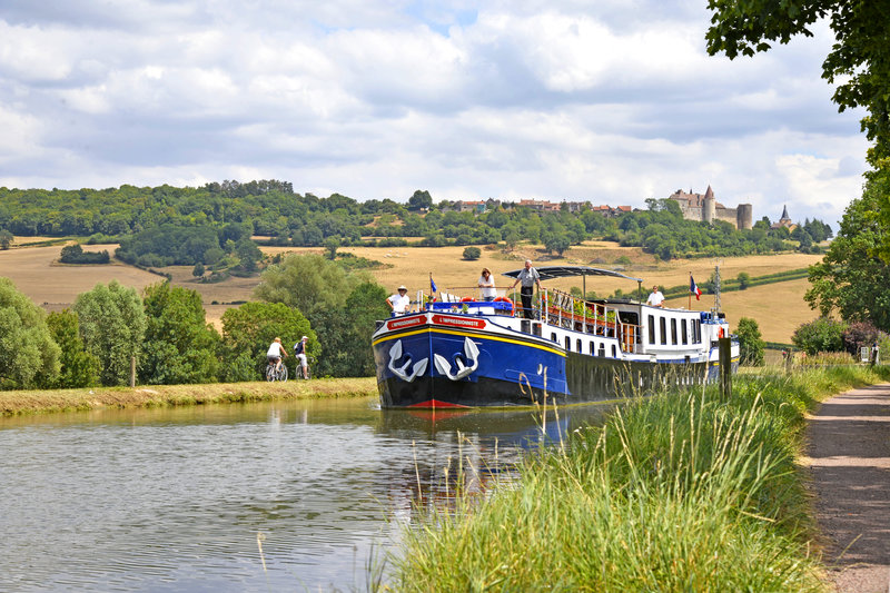 Luxury hotel barge, L'Impressionniste cruising past chateuneuf in Burgundy, France