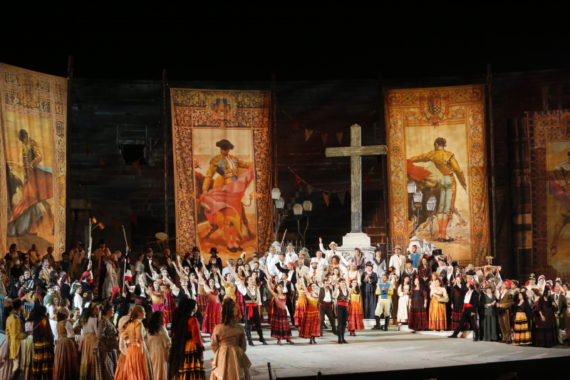 Cast of Carmen on stage at Arena di Verona, drapes of bull-fighting at back