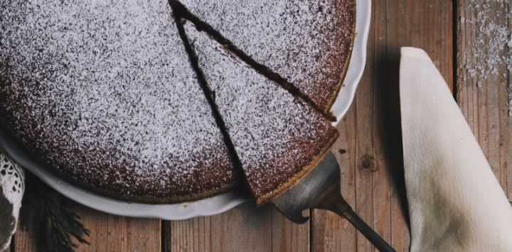 Chocolate torte with sieved icing sugar and one slice being taken