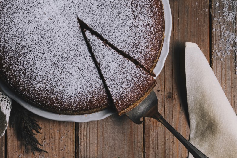 Chocolate torte with sieved icing sugar and one slice being taken