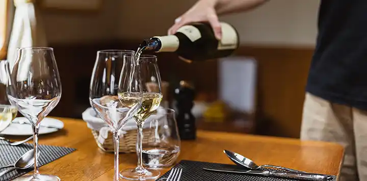 Host pouring wines at the dinner table