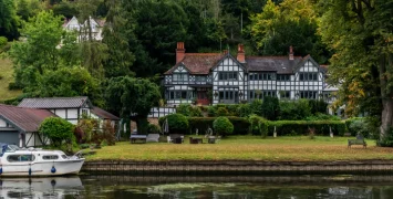 40th anniversary cruise on Magna Carta on the River Thames England. Cruising past Judith Potts medieval style manor house.
