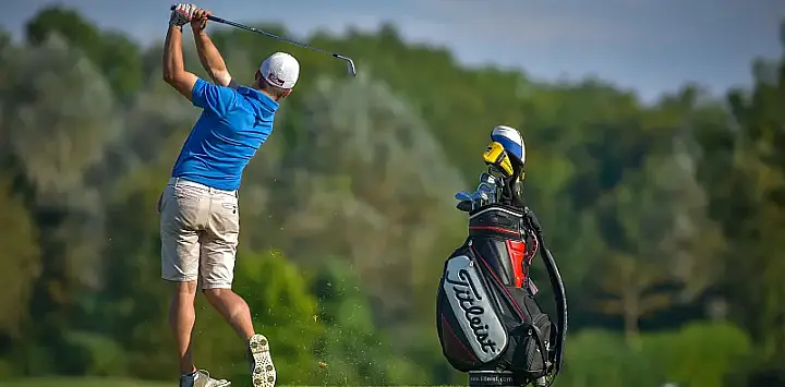 Person hitting a ball with their bag next to them
